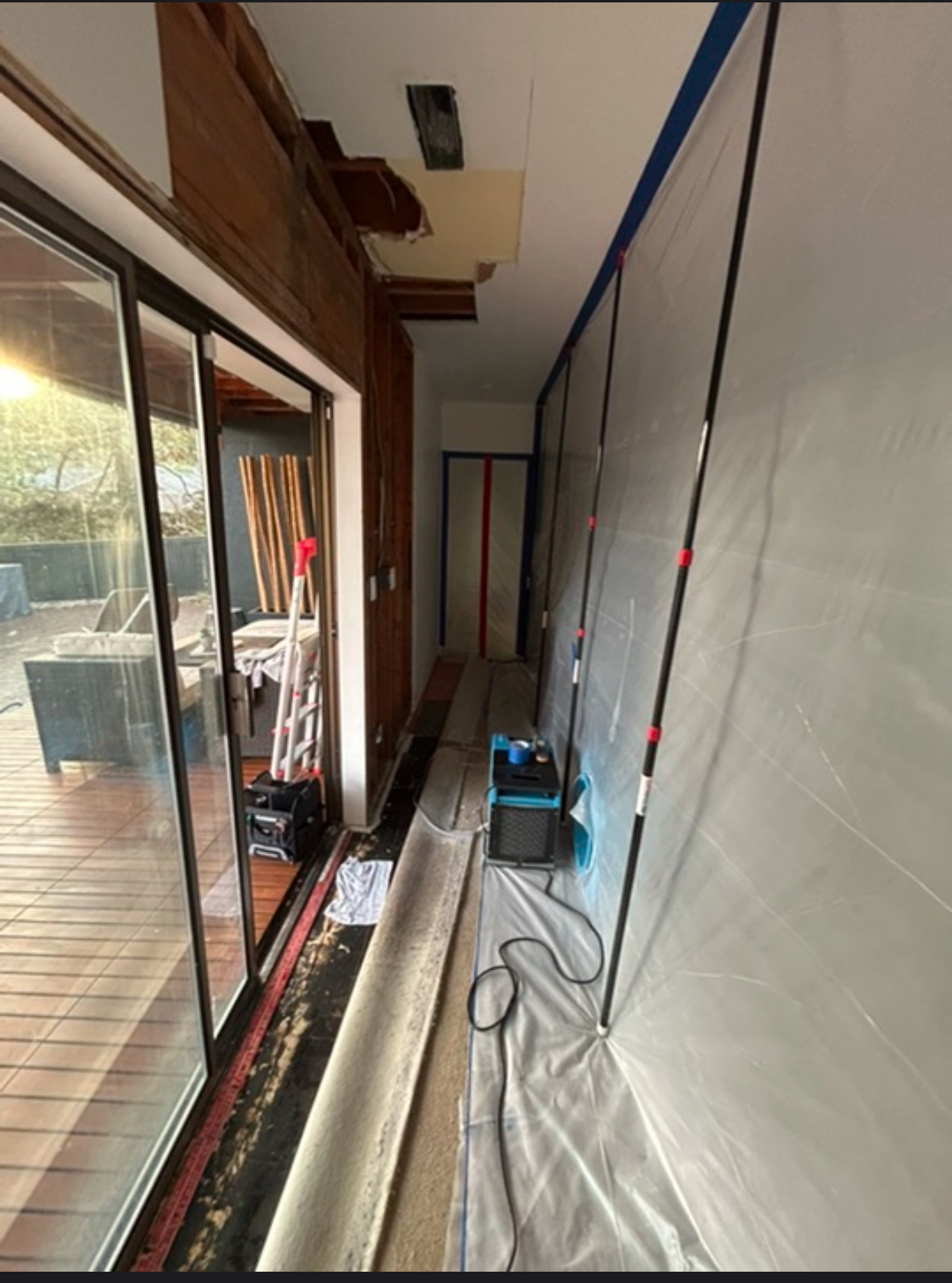 Water damage restoration in hallway with containment barriers