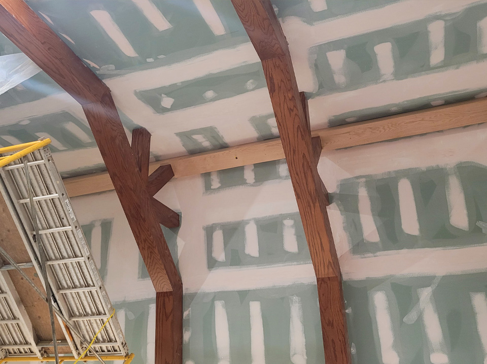 9. With the demo done, and mold remediation complete, our team installed mold resistant drywall to the ceiling, and the homeowner asked if we could install an oak beam along the ridge to match the others. 