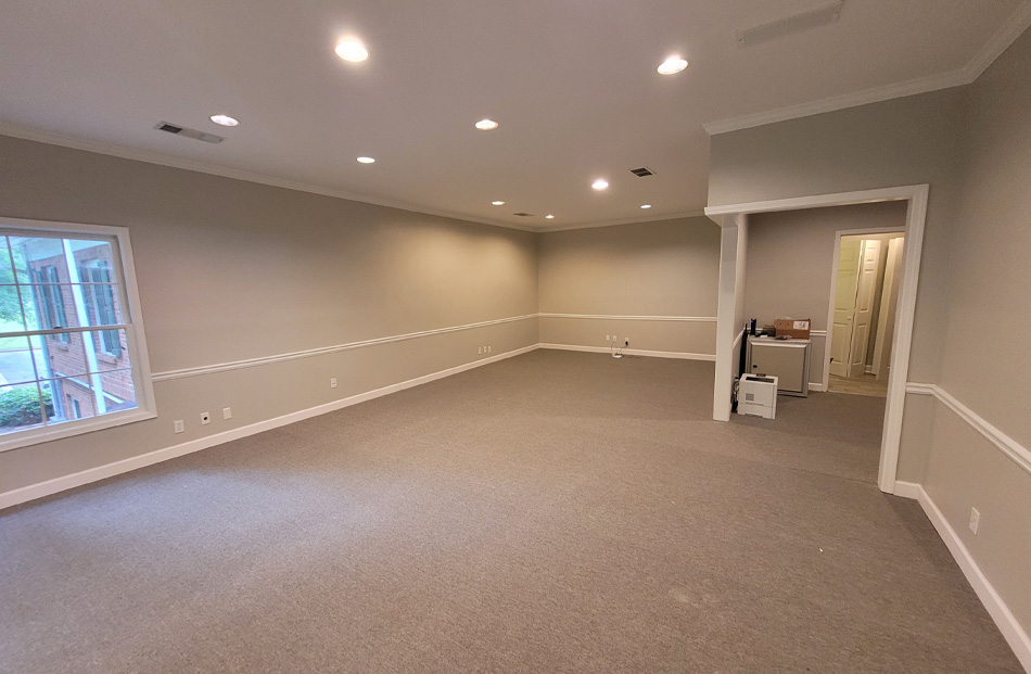 Spacious, modern empty room with carpet and recessed lighting.