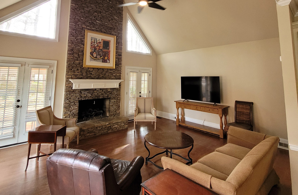 Spacious living room with stone fireplace and high ceilings.